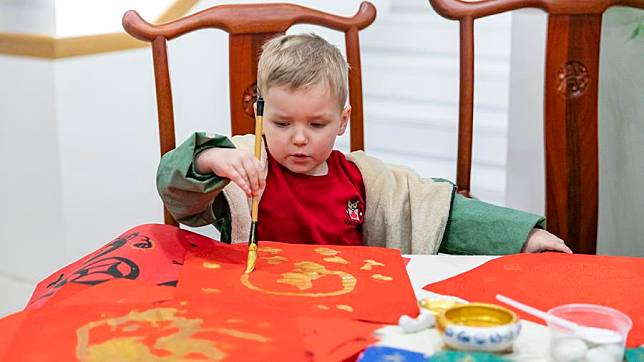 A kid writes Chinese character &ldquo;Fu,&rdquo; which means good fortune, during an exhibition on the Chinese zodiac at the China Cultural Center in Belgrade, Serbia on Feb. 12, 2025. (Photo by Wang Wei/Xinhua)