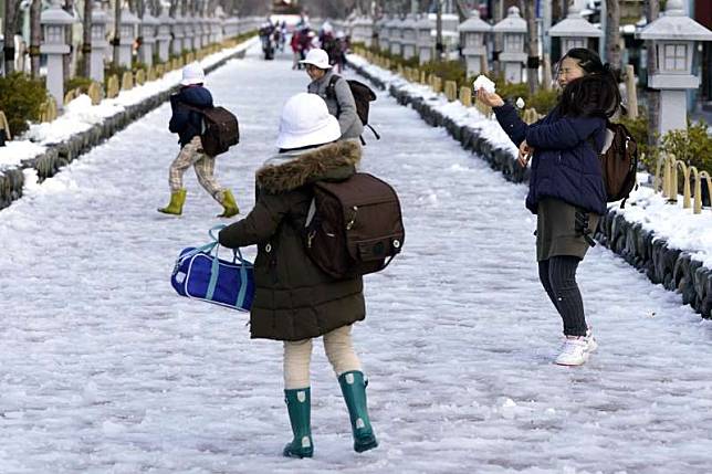 日本大雪，小學生開心在路上玩雪，天再冷，還是著裙裝。（美聯社）