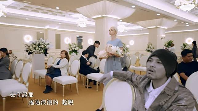黃明志(右)新歌MV中，金髮美女現身他的告別式。(翻攝自YouTube)