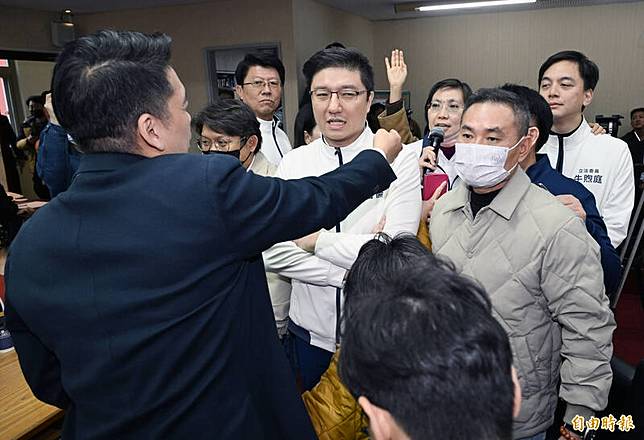 內政委員會召委徐欣瑩(持麥克風者)在多位國民黨男立委護衛下，進入會議室後方以自備麥克風宣布延長開會；占領主席台的民進黨立委喊口號加以干擾，強調會議尚未開始。(記者廖振輝攝)