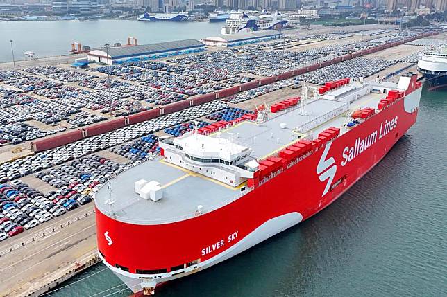 An aerial drone photo taken on Aug. 6, 2024 shows commercial vehicles to be exported beside a ro-ro ship at Yantai Port in east China's Shandong Province. (Photo by Tang Ke/Xinhua)