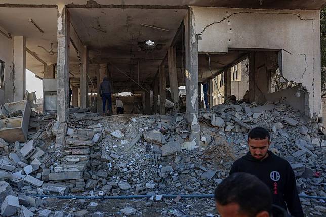 People are seen at a building destroyed in an Israeli bombing in the center of the southern Gaza Strip city of Khan Younis, on Jan. 2, 2025. (Photo by Rizek Abdeljawad/Xinhua)