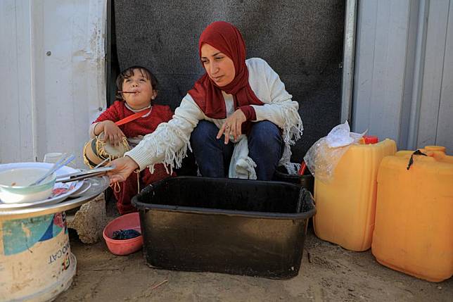 A woman washes dishes at a temporary camp in the southern Gaza Strip city of Rafah, on March 8, 2024. (Photo by Rizek Abdeljawad/Xinhua)