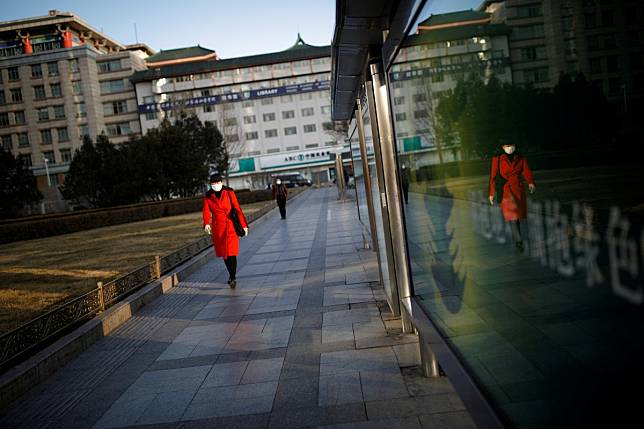 A woman wearing a face mask walks past office buildings in Beijing. Photo: Reuters