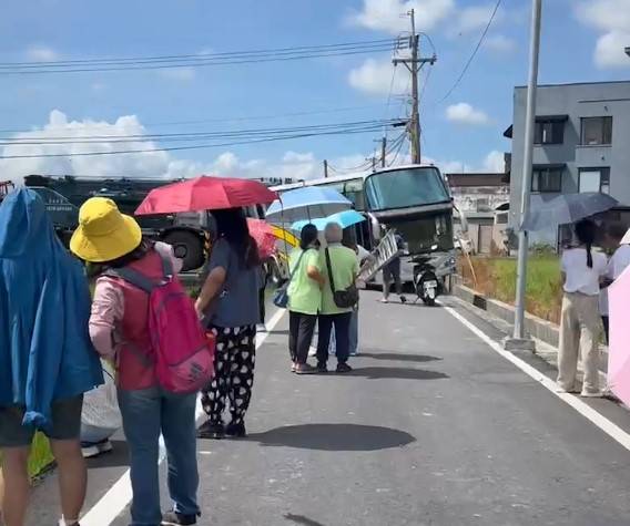 搭遊覽車來宜蘭的乘客在車輛卡水溝後下車等待。（民眾提供）