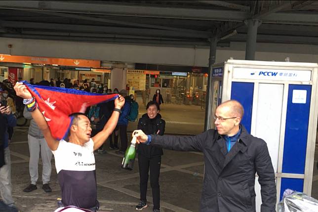 Nugo Yamanath Limbu, the first finisher at the Hong Kong Four Trails Ultra Challenge (Hk4TUC) 2020, being passed Champagne by organiser Andre Blumberg. Photo: Mark Agnew