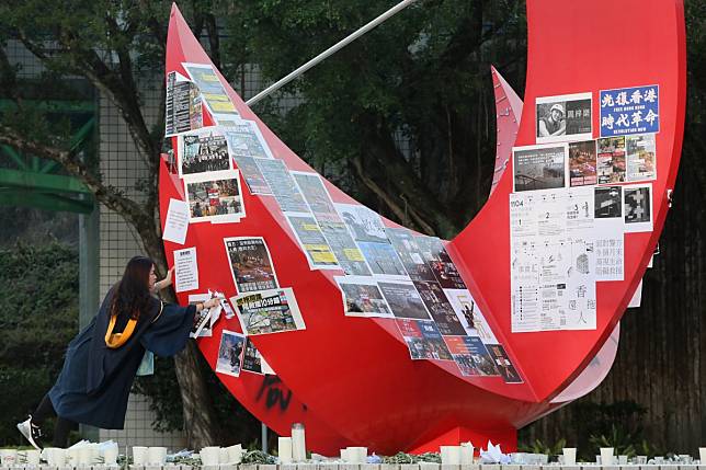 A recent graduate takes down anti-government posters at Hong Kong University of Science and Technology. Photo: Felix Wong