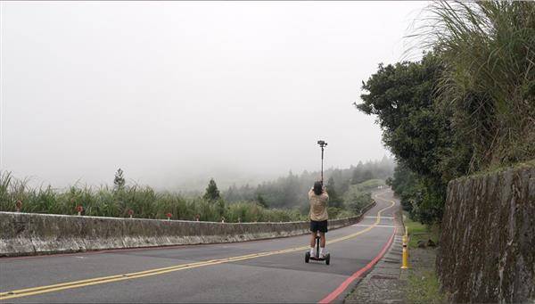 攝影師站在電動平衡車上，以iPhone加上延伸腳架，捕捉陽明山中湖戰備道的景色。（圖片來源／蘋果提供）