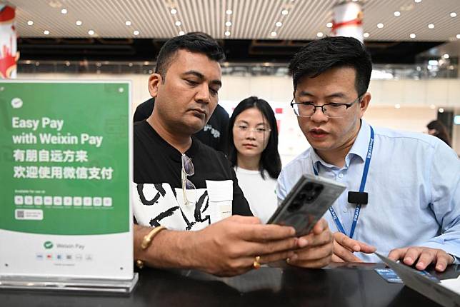 An Indian passenger (L) asks for information on a China's major mobile payment platform at Terminal 2 of Guangzhou Baiyun International Airport in Guangzhou, south China's Guangdong Province, April 3, 2024. (Xinhua/Deng Hua)