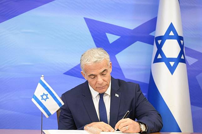以色列總理拉皮德在協議書上簽字   圖：翻攝自以色列外交部推特