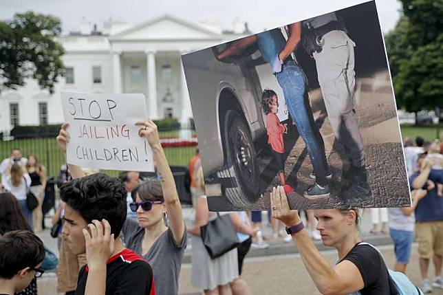 6月21日，美國民眾舉著印了宏都拉斯2歲女童在邊境哭泣照片的標牌在白宮前抗議（美聯社）