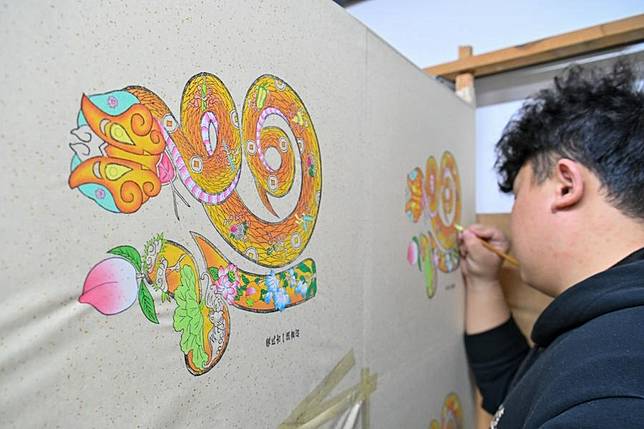 An artist paints a new year picture at a picture shop in Yangliuqing Town, Tianjin, north China, Jan. 20, 2025. (Xinhua/Sun Fanyue)