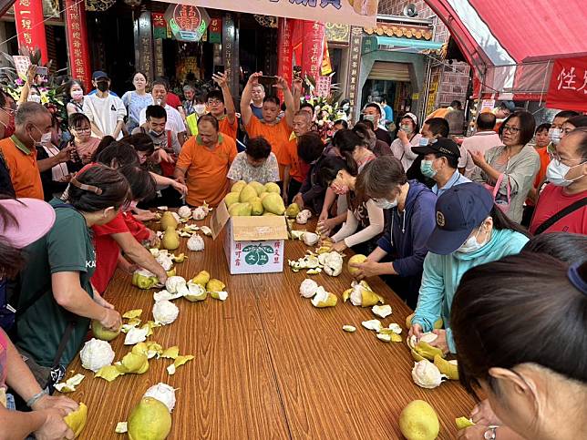 頂土地廟每年中秋節例行趣味競賽剝柚子大賽，昨天上午在廟前廣場熱鬧展開。（記者陳俊文攝）