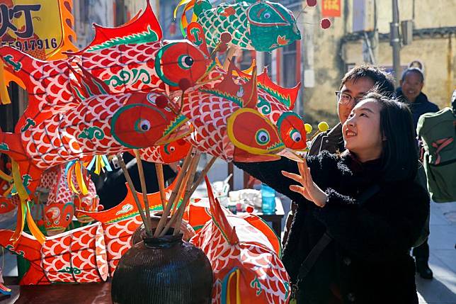 Tourists select fish-shaped lanterns at Zhanqi Village in Shexian County of Huangshan City, east China's Anhui Province, Jan. 18, 2025. (Photo by Fan Chengzhu/Xinhua)