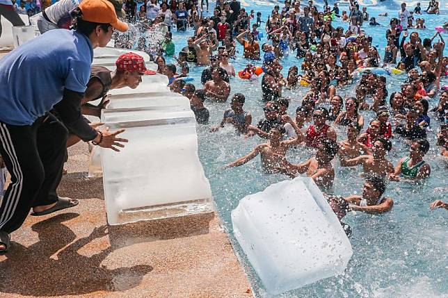 Staff members put ice blocks into a swimming pool at a resort in Bulacan Province, the Philippines, on May 5, 2024. (Xinhua/Rouelle Umali)