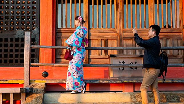 一名男子在日本京都的清水寺，為身著和服的朋友拍照。美聯社