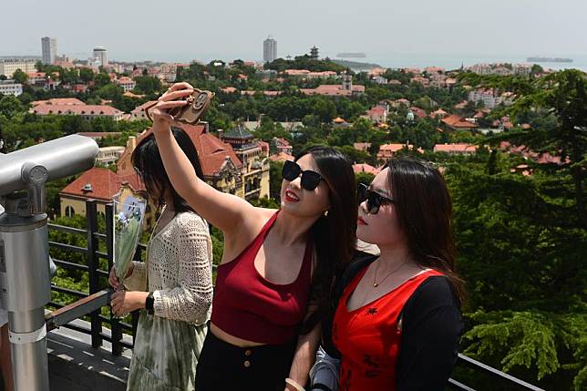 Tourists pose for a selfie at the Xinhao Mountain scenic spot in Qingdao, east China's Shandong Province, June 24, 2024. (Photo by Wang Haibin/Xinhua)