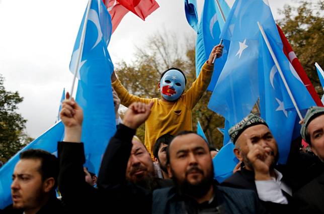 多名維吾爾族人在土耳其高舉「東突厥斯坦」旗幟抗議。（湯森路透）