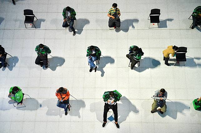 Staff of food delivery companies sit on social distancing chairs due to coronavirus disease (COVID-19) outbreak, as they wait for their costumers' orders at a department store in Bangkok