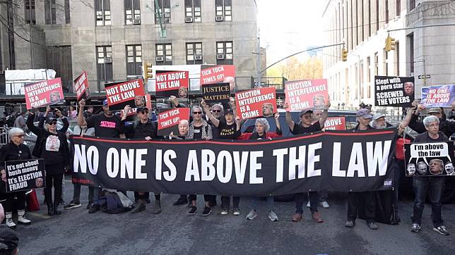 A video screenshot shows a group of former U.S. President Donald Trump's critics marching by New York County Criminal Court in New York, the United States, on April 15, 2024. (Photo by Ding Ye/Xinhua)