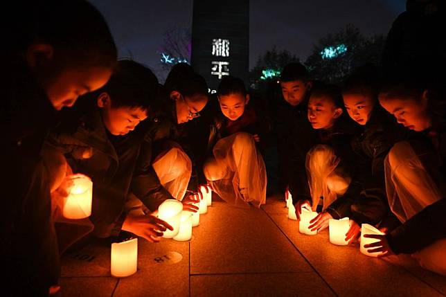 Children place candles while attending a candle light vigil at the Memorial Hall of the Victims in Nanjing Massacre by Japanese Invaders in Nanjing, capital of east China's Jiangsu Province, Dec. 13, 2024. A candle light vigil was held here on Friday to mark this year's national memorial day for the victims of the Nanjing Massacre. (Xinhua/Ji Chunpeng)