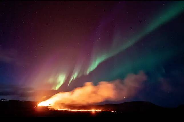 ▲冰島西南端的雷克雅內斯半島持續噴發，更與極光同時被攝影師捕捉，橘黃火焰與碧綠極光相互輝映，非常壯觀。（圖／美聯社／Marco Di Marco）