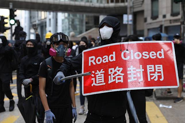 A protester holds a street sign during a march against the Hong Kong police. Photo: EPA-EFE