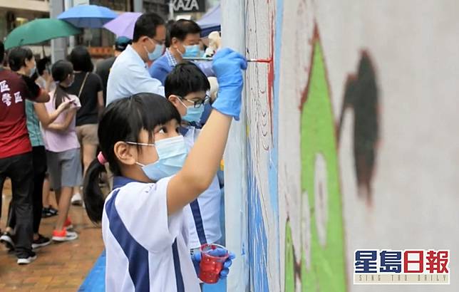 小孩專心地為西區警署牆壁上畫有宣傳道路安全的圖畫塗上顏色。