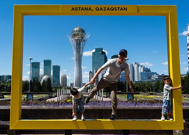 A man plays with two boys at an installation at the city's central axis in Astana, Kazakhstan, June 29, 2024. (Xinhua/Wang Jianhua)