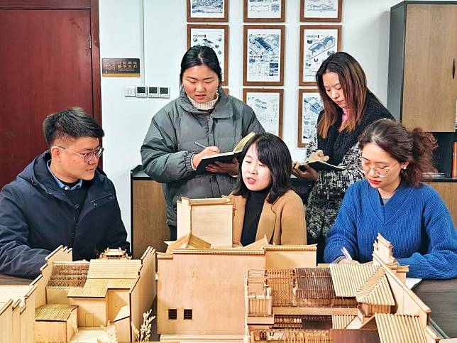 Xuan Wei(C front), dean of College of Architecture & Art, Hefei University of Technology, discusses the modeling of ancient Hui-style architecture with her colleagues in Hefei, east China's Anhui Province, Jan. 8, 2024. (Xinhua/Guo Chen)