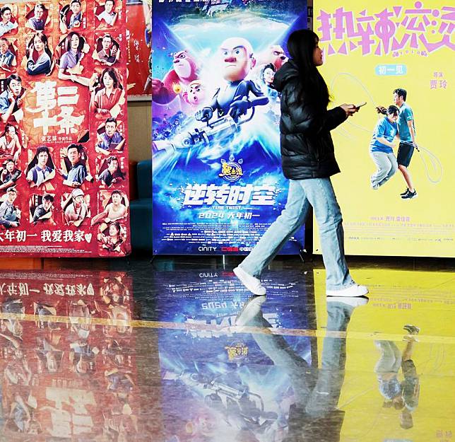 A woman walks past film posters at a cinema in Tancheng County of Linyi City, east China's Shandong Province, Feb. 15, 2024. (Zhang Chunlei/Xinhua)