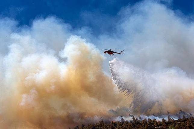 A firefighting helicopter drops water on a wildfire in Dione near Athens, Greece, Aug. 12, 2024. (Xinhua/Marios Lolos)