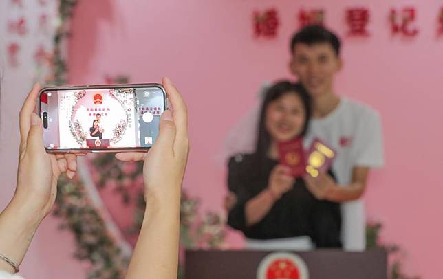 A couple pose for photos with their marriage certificates at a marriage registration office in Kaiyang County, southwest China's Guizhou Province, Aug. 22, 2023. (Photo by Yuan Fuhong/Xinhua)