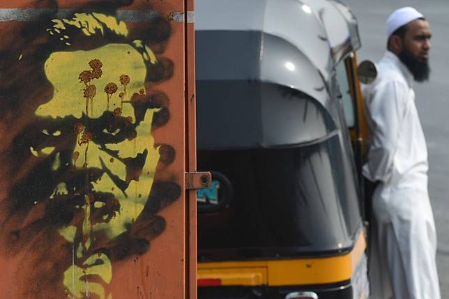 A Muslim auto-rickshaw driver waits for customers next to graffiti of Indian Prime Minister Narendra Modi by street artist “Tyler” created in the wake of nationwide protests against India's new citizenship law, in Mumbai on Tuesday. Photo: AFP