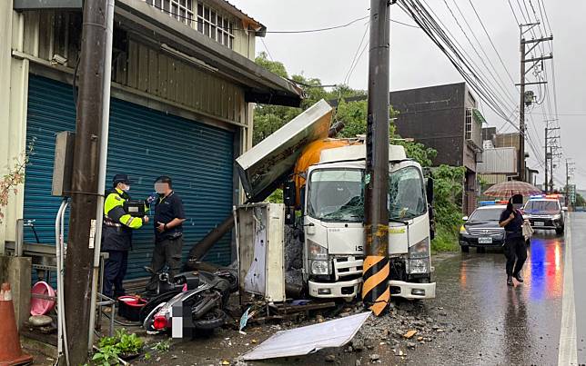 楊梅一部大貨車因天雨視線不佳，撞斷路邊的招牌和電桿。（記者丘安翻攝）