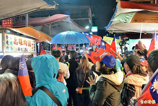 韓粉手持國旗站在廟埕前的夜市街道上，因逛街的遊客走不過去，還有商家請停在攤前的韓粉讓路給客人走。(記者許麗娟攝)