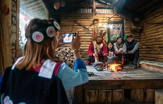 He Yuyue (L) takes photo of her father He Jielin and tourists at home in Yuhu village, Lijiang City, southwest China's Yunnan Province, March 27, 2024. (Xinhua/Chen Xinbo)