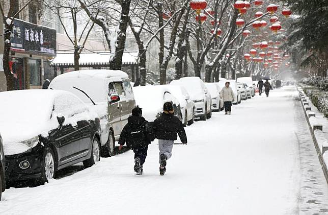 Children run on a street in the snow in Luoyang, central China's Henan Province, Feb. 21, 2024. (Photo by Kang Hongjun/Xinhua)