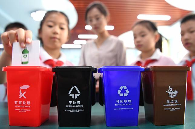 Pupils take part in a waste sorting game as part of an effort to encourage people to separate their rubbish, which had led to a surge in production of plastic bins. Photo: Xinhua