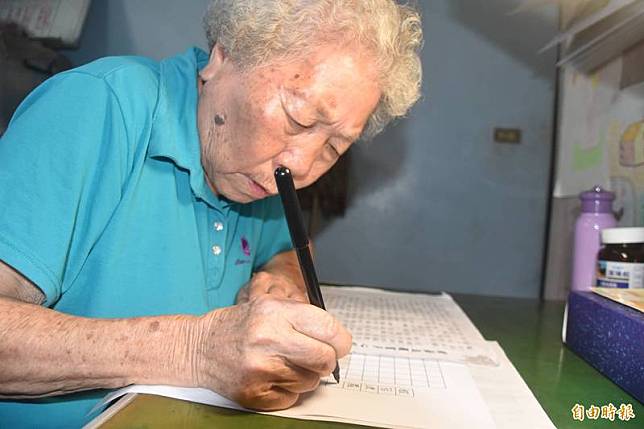 90歲阿嬤黃葉水花每天早上坐在書桌前，聚精會神抄寫經文。(記者蘇福男攝)