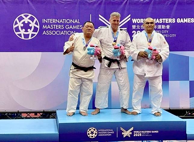 邱健安（左）出戰世界壯年運動會柔道男子一百公斤級比賽，勇奪銀牌。（消防局提供）