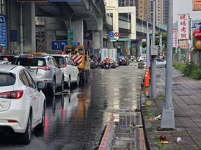 新北市新莊區新北大道跟思源路交叉口，今早自來水管破裂，造成路面淹水，適逢上班時間，路口交警協助交維。(圖由新莊區公所提供)