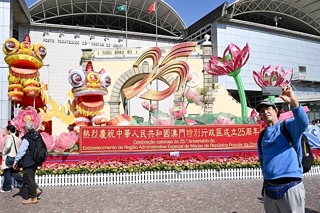 A tourist takes selfies in front of a celebration installation at the Border Gate in Macao, south China, Dec. 18, 2024. The streets of Macao have been adorned by festive decorations, as the city is set to mark the 25th anniversary of its return to the motherland. (Xinhua/Cheng Yiheng)