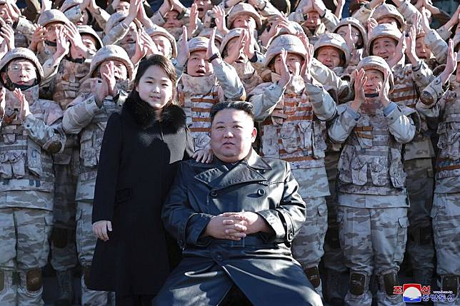 北韓官媒27日發布領導人金正恩和女兒視察飛彈試射後和官兵的團體照。（美聯社）