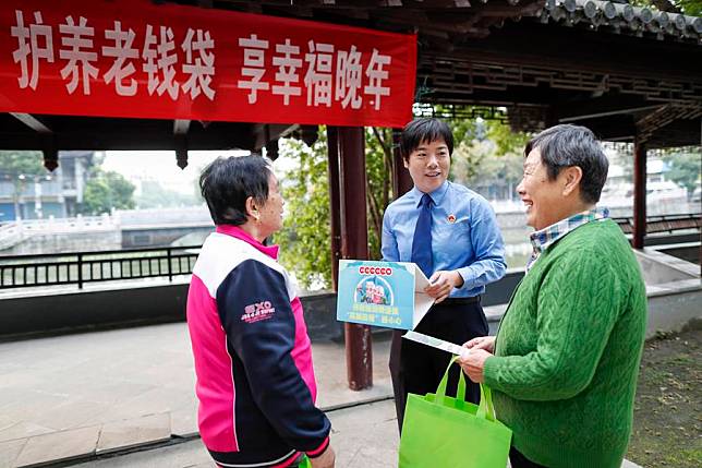 A police officer shares information on how to prevent telecom and internet fraud with local elderly residents at a park in Xinghua City, east China's Jiangsu Province, Oct. 10, 2024. (Photo by Zhou Shegen/Xinhua)