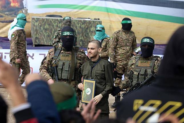 Members of the Al-Qassam Brigades, the armed wing of Hamas, and an Israeli hostage are seen during the handover of three Israeli hostages to the International Committee of the Red Cross, in the al-Nuseirat refugee camp, in central Gaza, on Feb. 22, 2025. (Photo by Rizek Abdeljawad/Xinhua)