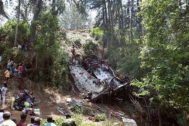 Onlookers watch as rescue workers search the debris at the site of a bus crash near the town of Kotmale, Sri Lanka Sunday, May 11, 2025. (AP Photo)