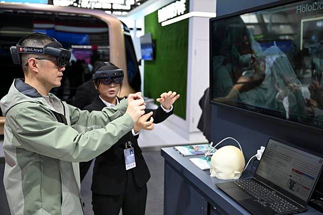 A visitor tries his hands on a holographic intelligent medical imaging system under the guidance of a staff member at the Light of Internet Expo in Wuzhen, east China's Zhejiang Province, Nov. 19, 2024. (Xinhua/Cai Xiangxin)