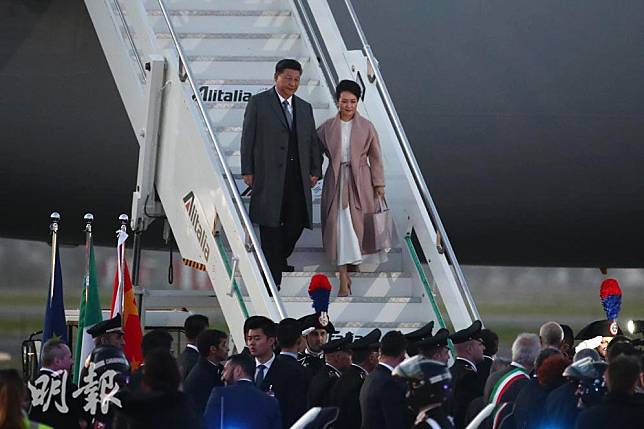 【習近平彭麗媛訪歐洲】2019年3月21日，中國國家主席習近平（左）與夫人彭麗媛（右）抵達意大利。彭麗媛以粉色長身大褸內襯白色長裙，造型優雅。（中新社）