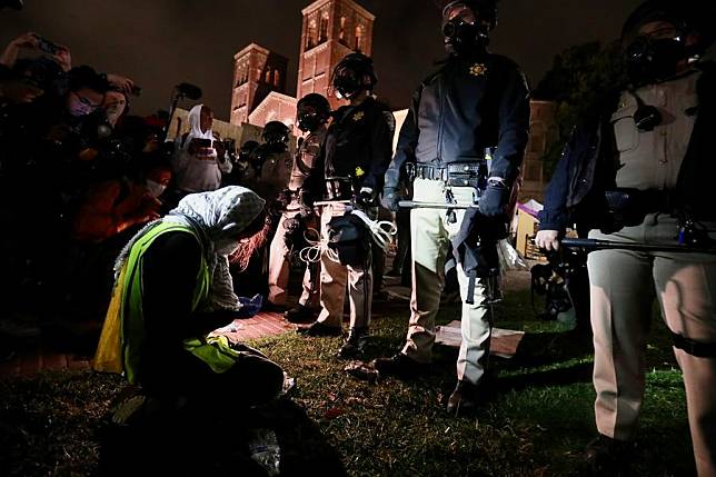 A pro-Palestinian protester kneels down in front of police officers outside an encampment of tents in support of Palestinians near Royce Hall of the University of California, Los Angeles (UCLA), in Los Angeles, California, the United States, on May 1, 2024. (Xinhua)